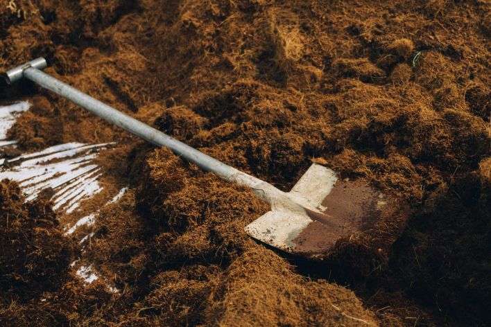 A shovel resting on a pile of nutrient-rich soil, ideal for gardening and planting.